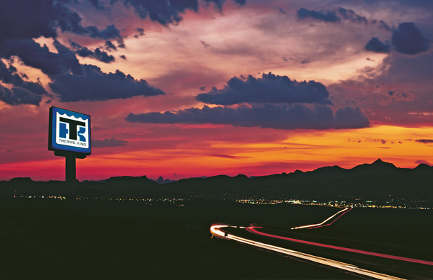 Photo at twilight of a Thermo King dealer sign lit up against the sunset and mountains.